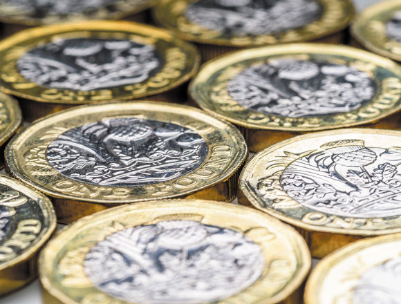 A selection of pound coins all lying flat.