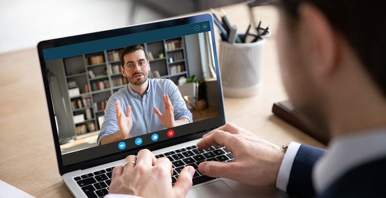 Business man wearing a suit is on a conference call on their laptop.