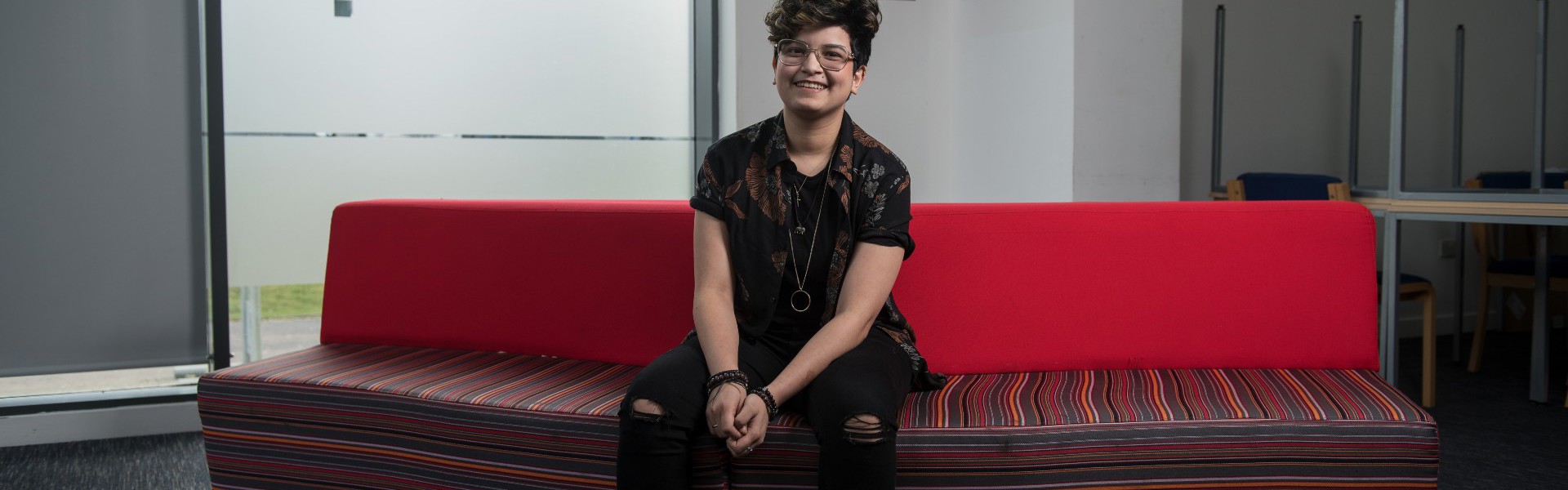 Yvannah sitting on a red sofa at college.