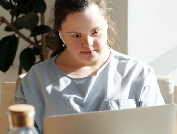 Student with earphones looking at their laptop at home.