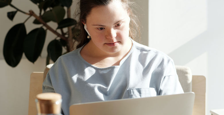 Student with earphones looking at their laptop at home.