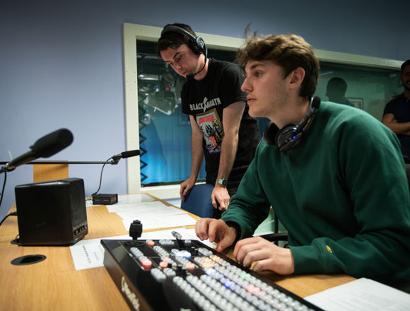 Broadcast media students producing a radio show in a studio.