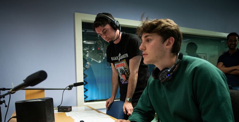 Broadcast media students producing a radio show in a studio.
