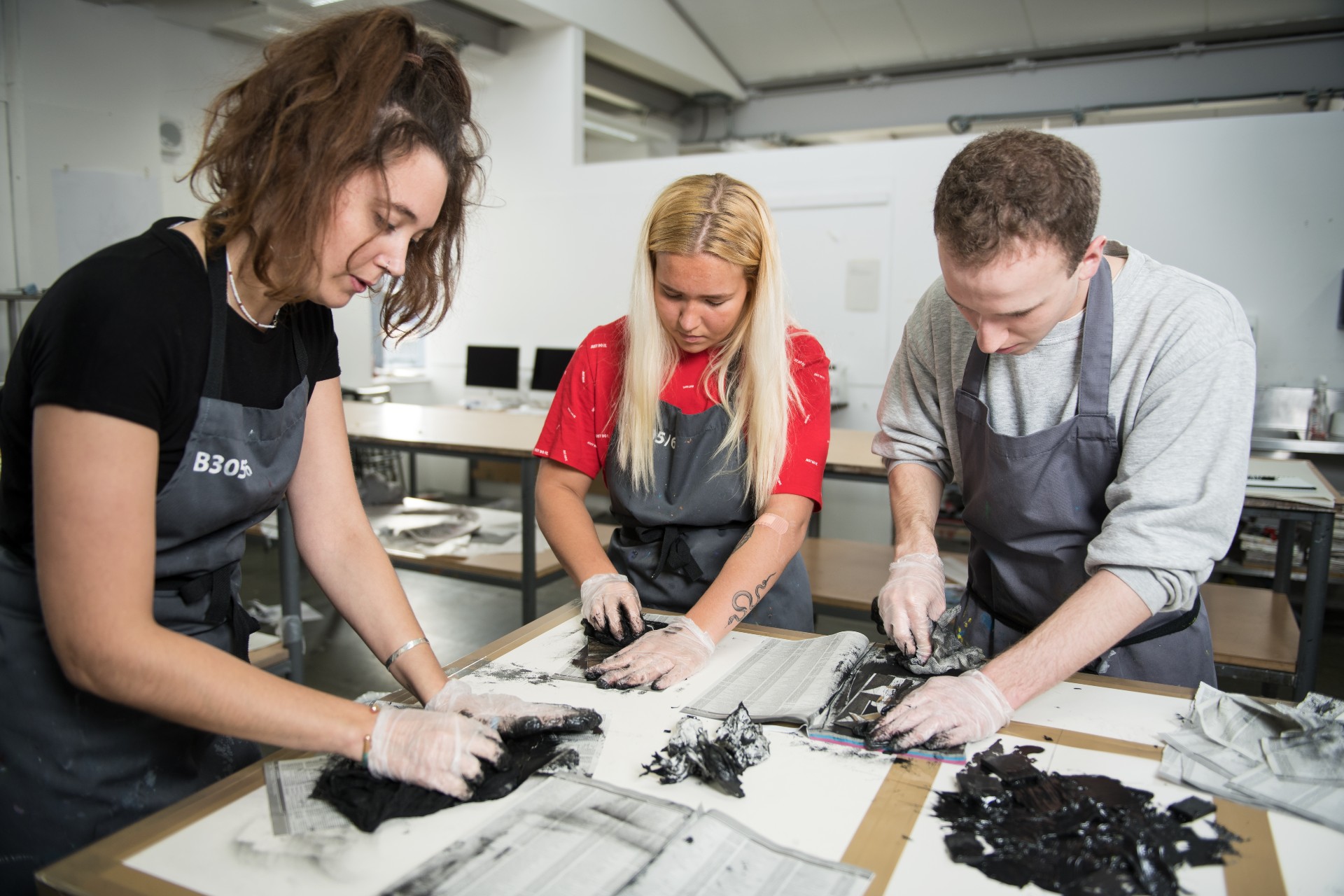 Three art students working together in an art studio classroom.