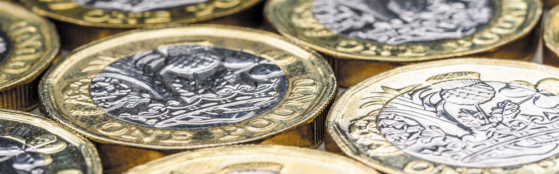 A selection of pound coins all lying flat.