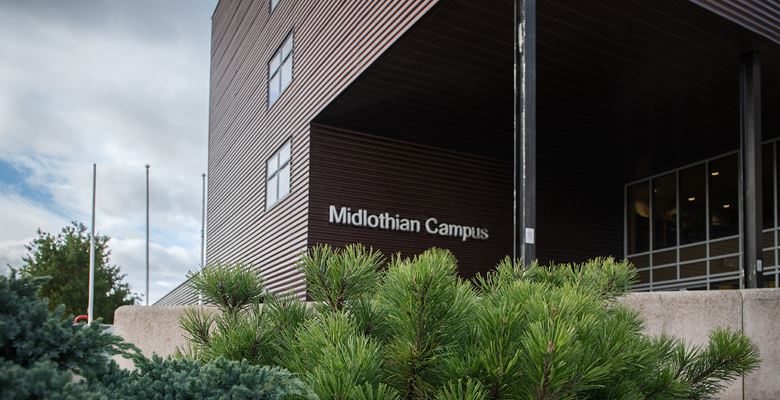 Shrubbery outside the Midlothian campus building, with the campus sign on the building.
