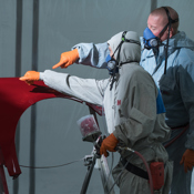 Two people wearing protective suits, masks and goggles.