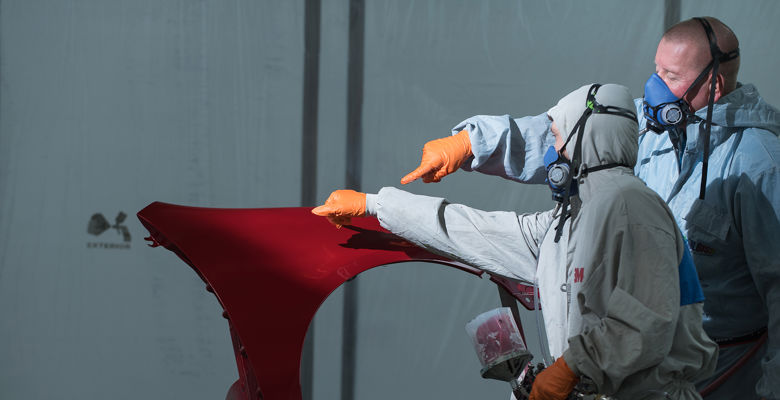 Two people wearing protective suits, masks and goggles.
