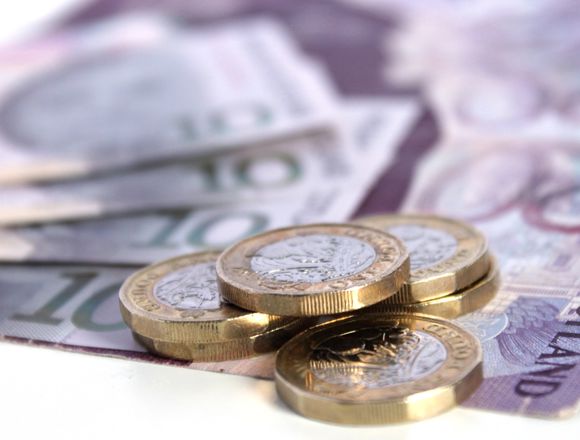 Pound coins on top of bank notes.