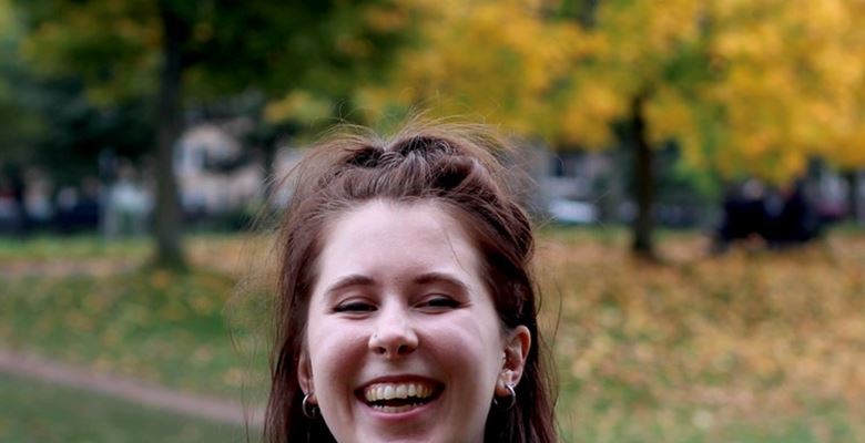 Graphic design student Gemma is smiling in a park.