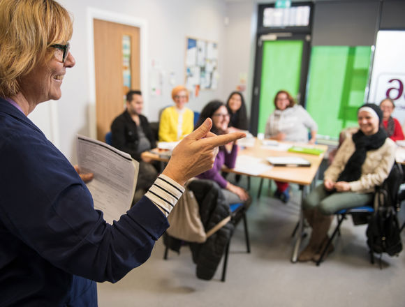 ESOL lecturer teaching in front of a classroom of students.