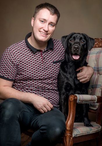 Photo of Alistair with their black Labrador dog.