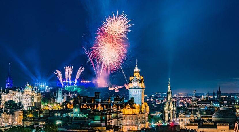 Bright fireworks against a dark blue sky and Edinburgh's skyline.
