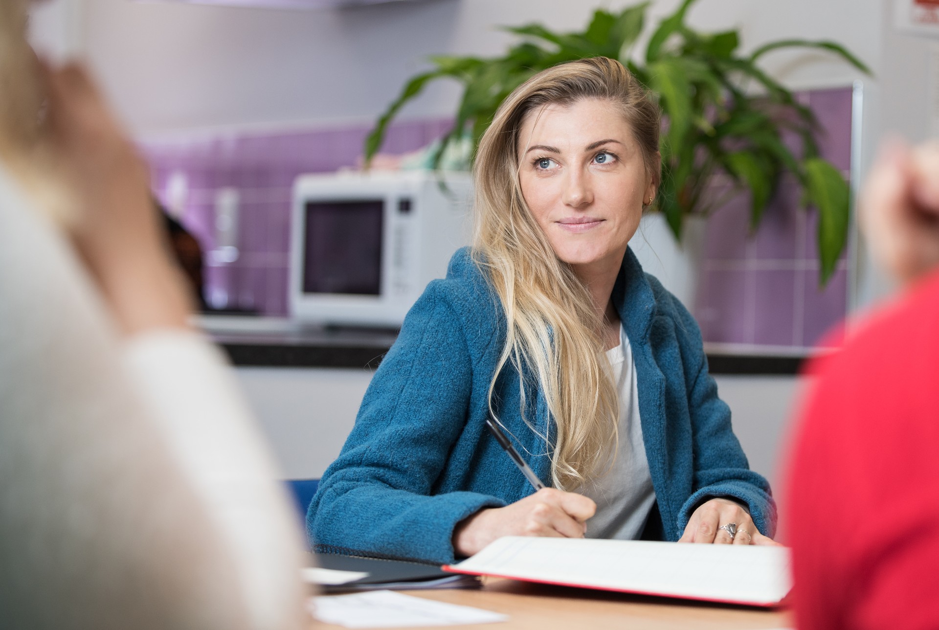 ESOL student with long blonde hair writing in notebook. 