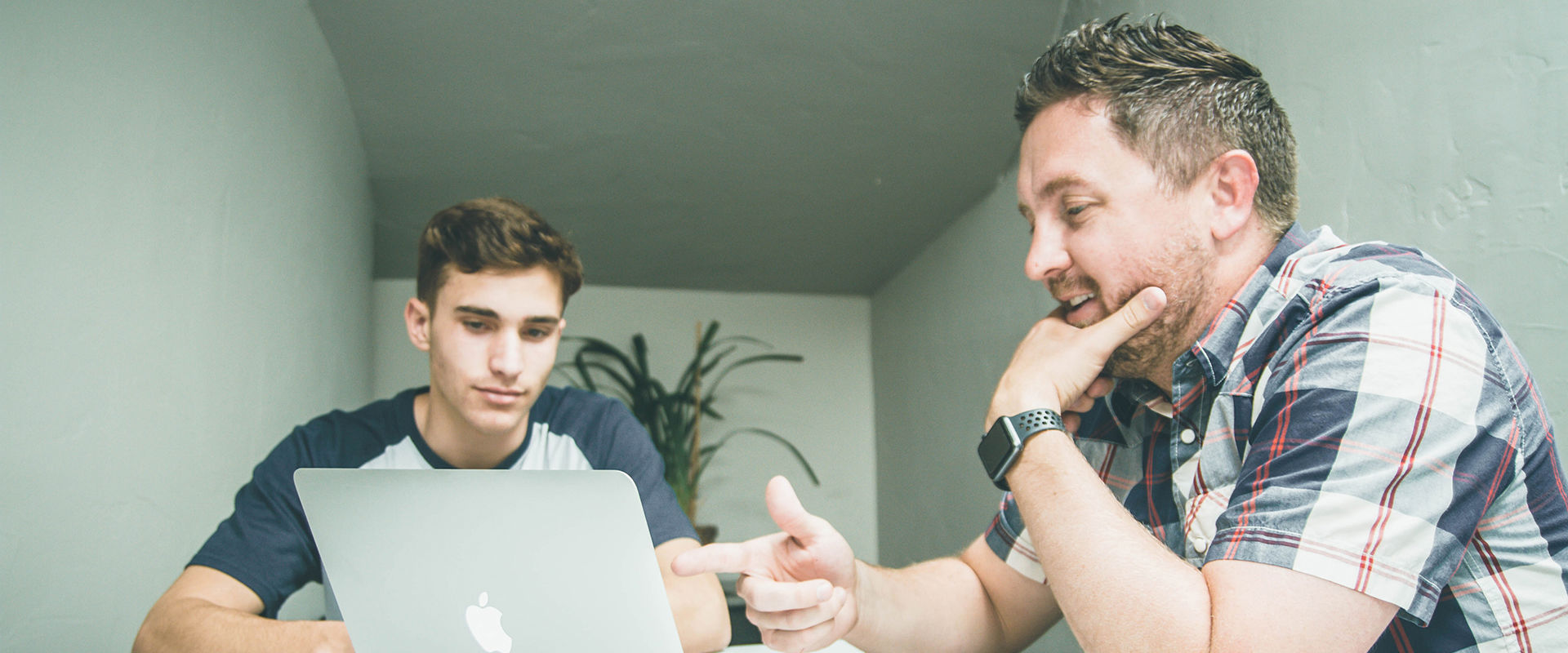 Lecturer is helping a student by showing them something on their laptop.