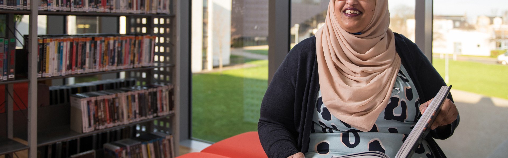 Khadijah sitting in the library with an open book.