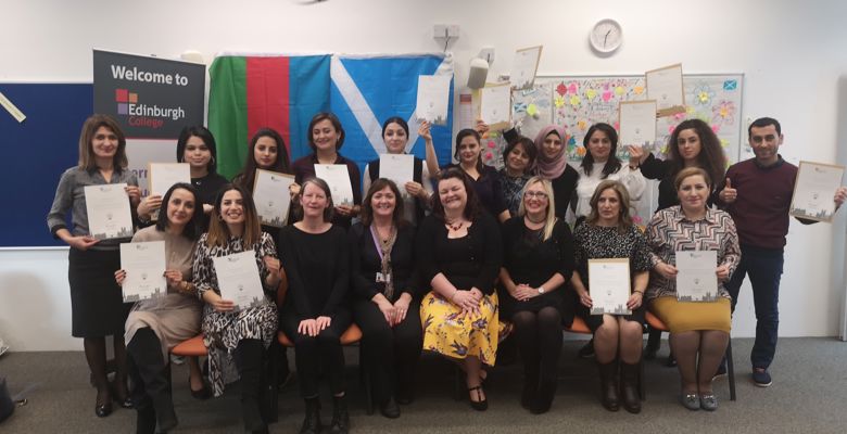 A group of diverse individuals proudly display their certificates, celebrating their achievements in front of a colorful backdrop.