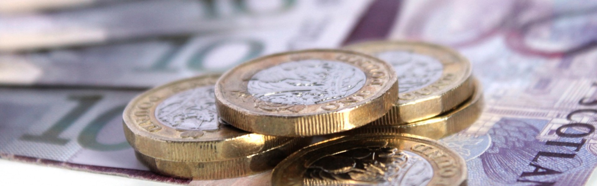 A stack of pound coins on top of bank notes.
