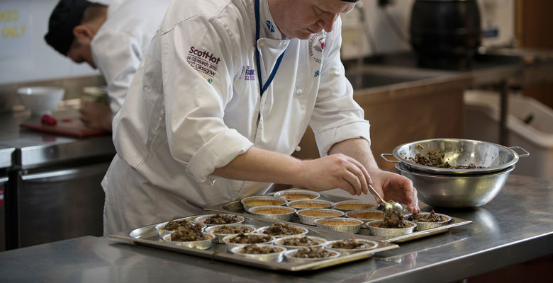 Cookery student preparing dishes in a training kitchen.