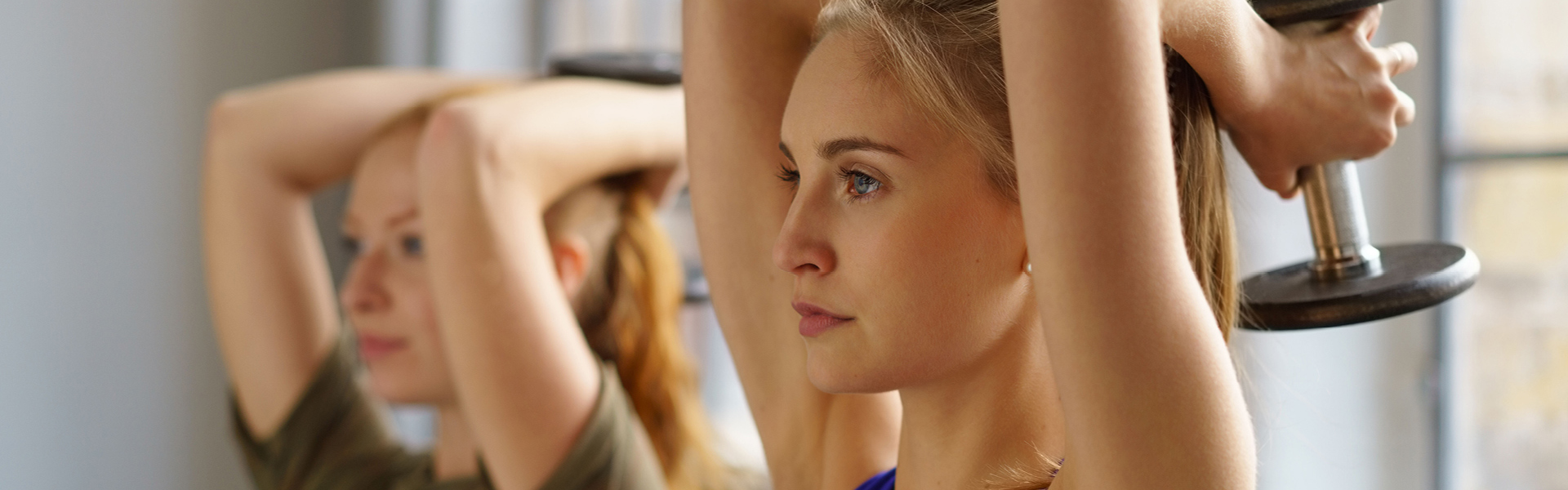 Two women using dumbbell weights during an exercise class.