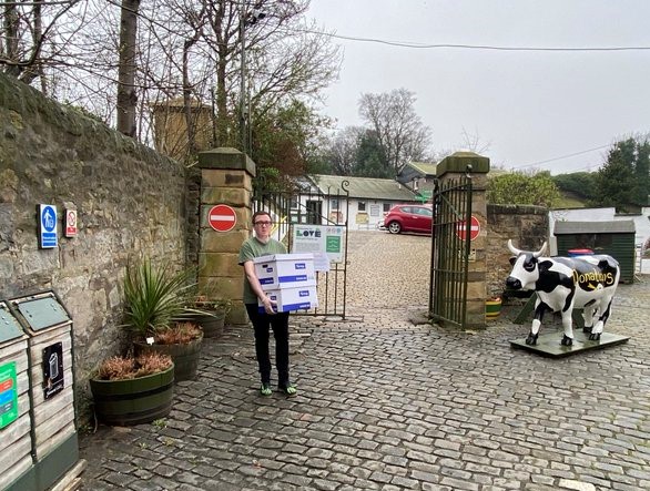 Person holding two cardboard boxes of donations.