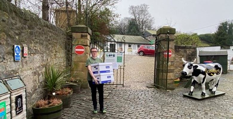 Student volunteer carrying two large white boxes, to be donated to local causes.