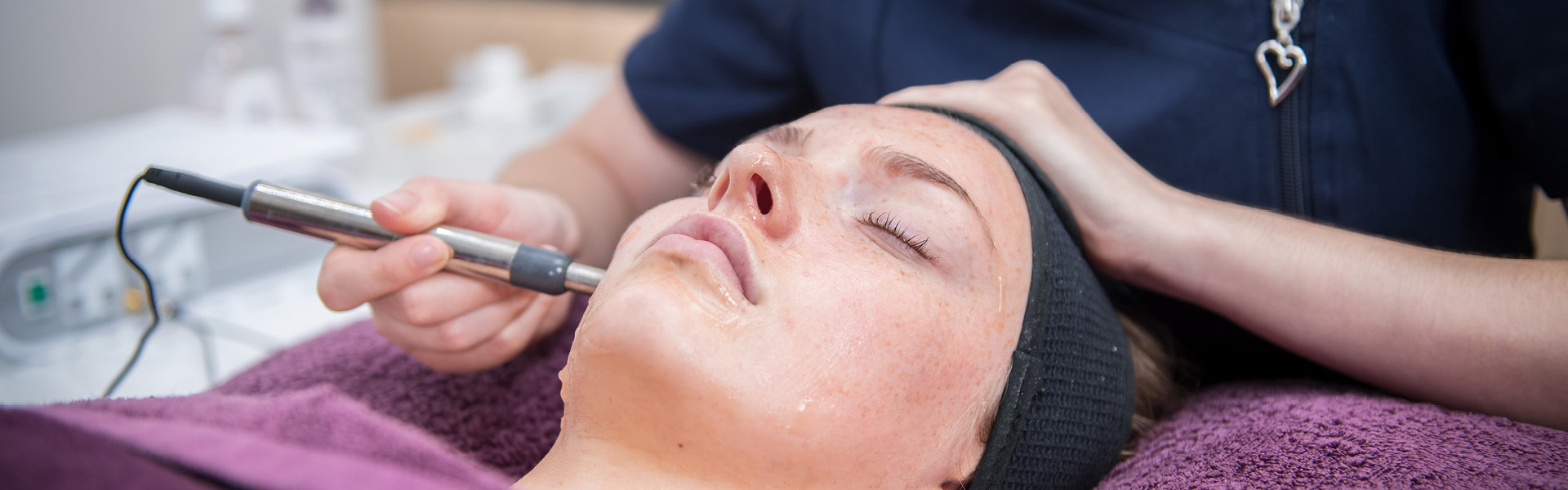 Close up of a beauty student preforming a procedure on a client's face.