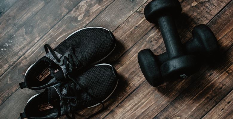 Black trainers and dumbbell weights on the floor.