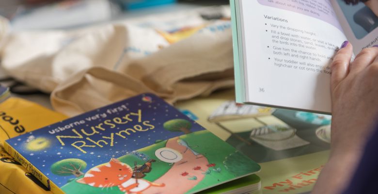Nursery rhymes book on a desk while a student is reading another book.