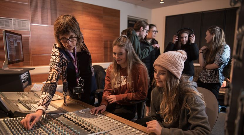Sound production lecturer showing two young students how to work equipment.