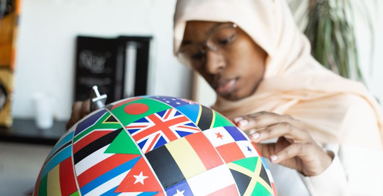 Person holding a globe with lots of different country's flags on it.