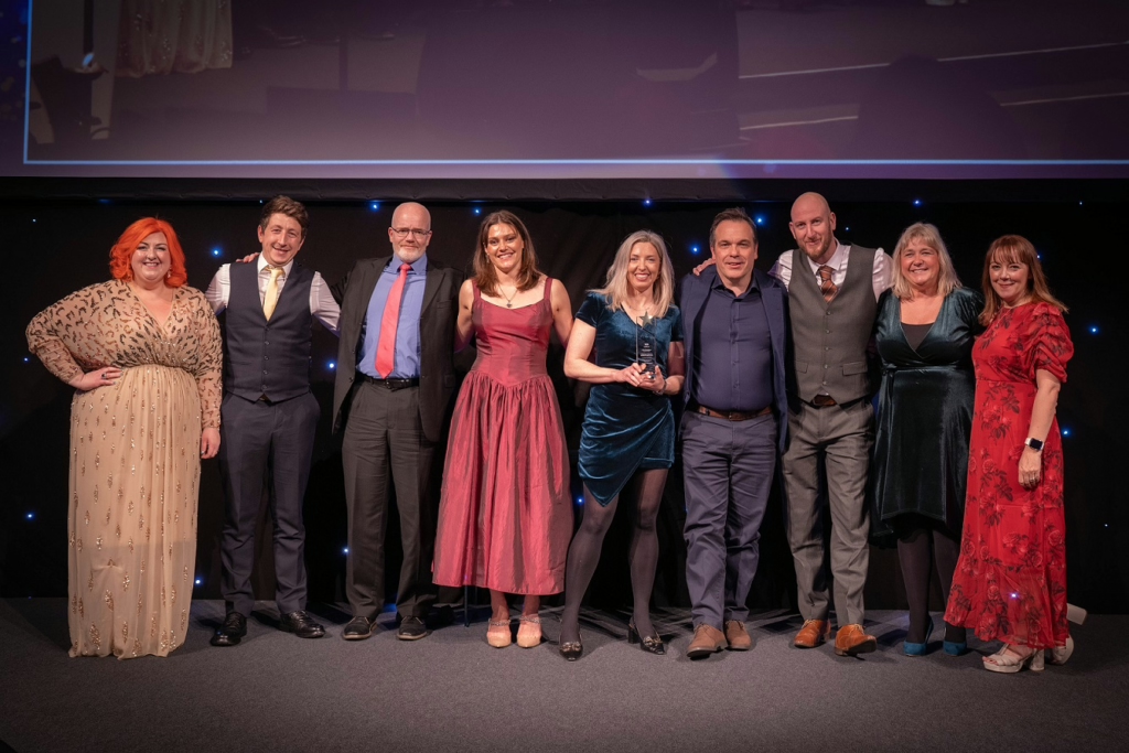Council and College staff smiling on a stage while accepting an award.