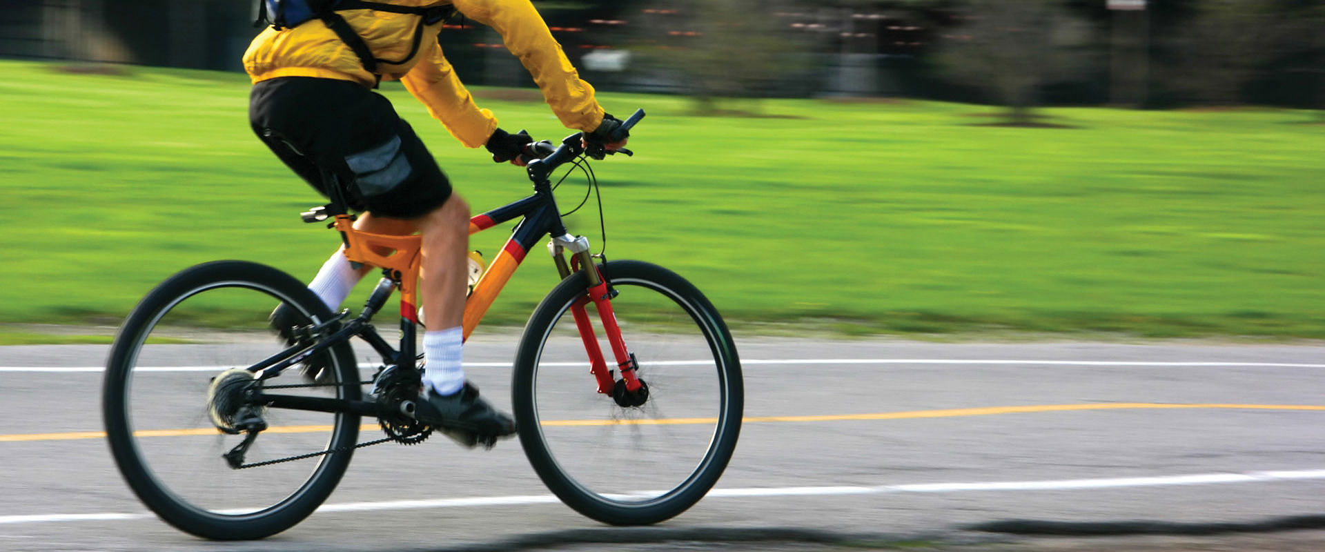Student wearing a bright yellow jacket and helmet is cycling to college.