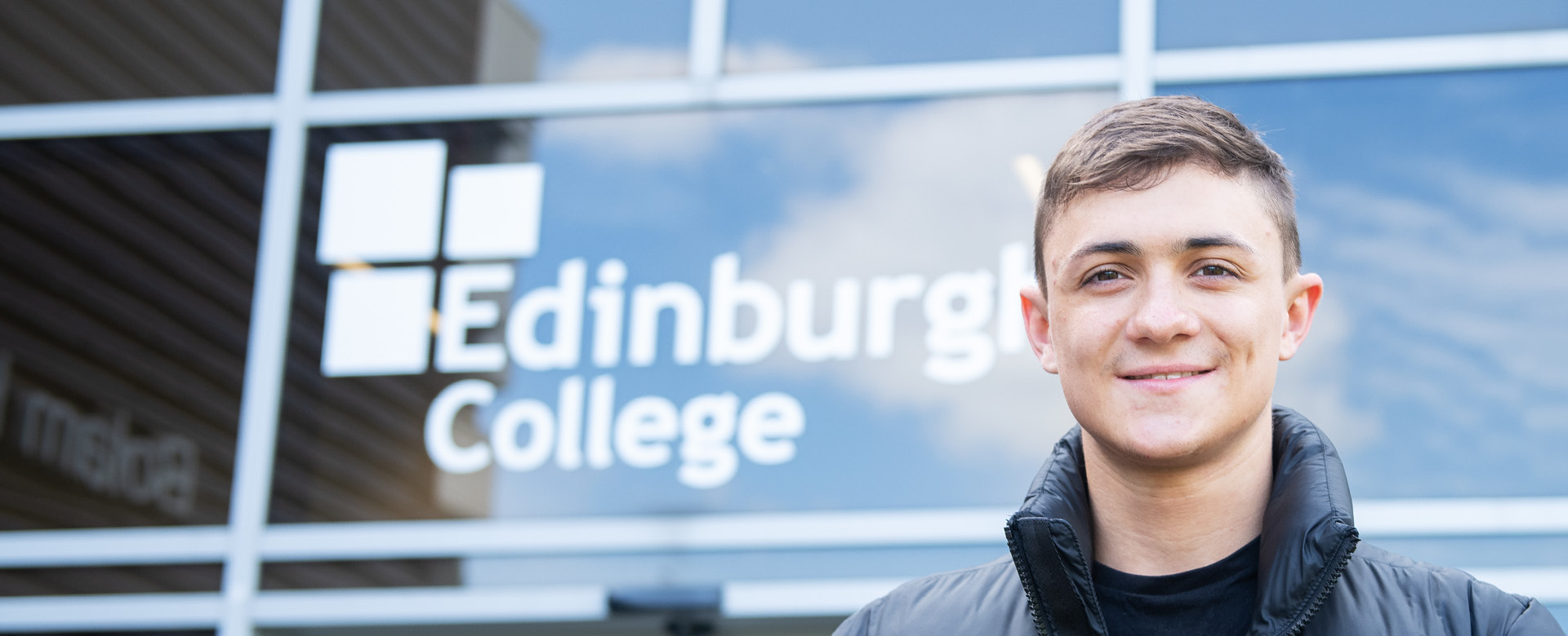 Young student standing outside a campus building.