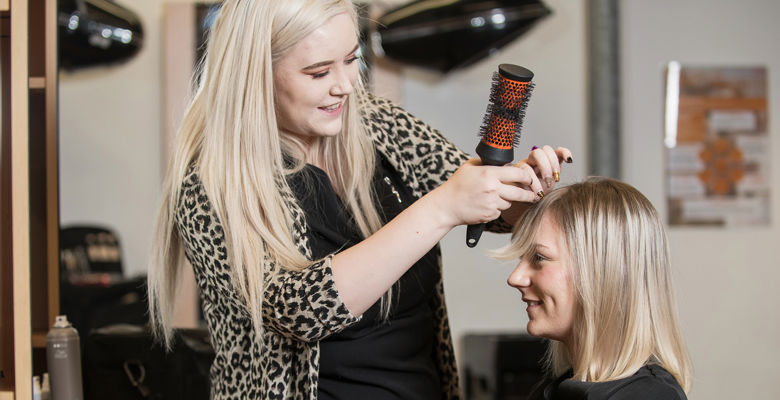 Hairdressing student brushing a client's hair in the salon.
