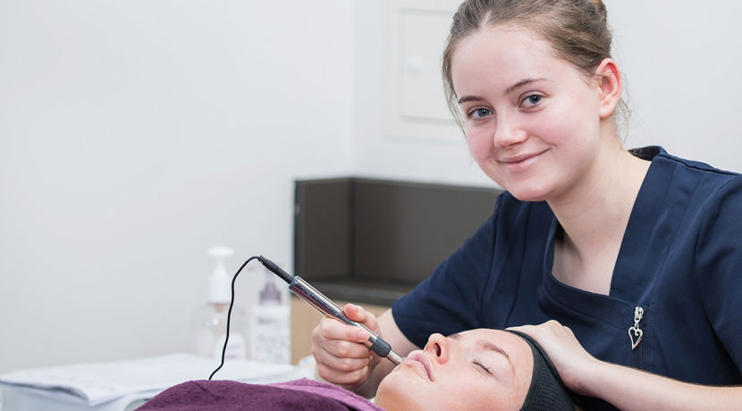 Beauty student preforming a procedure on a client's face. 