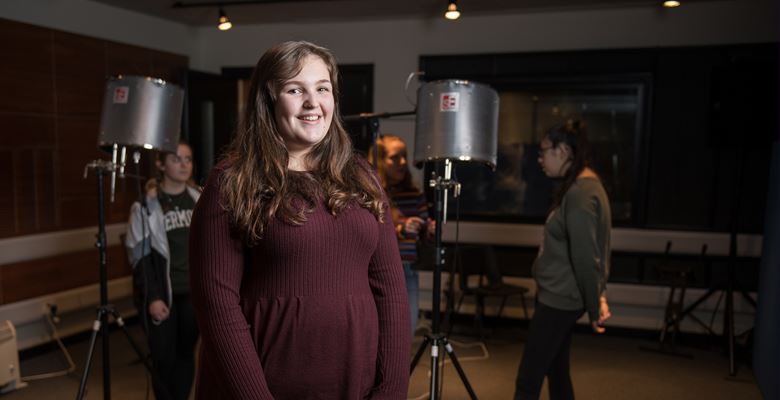 Music and Sound Production student standing in front of a microphone in a recording studio.
