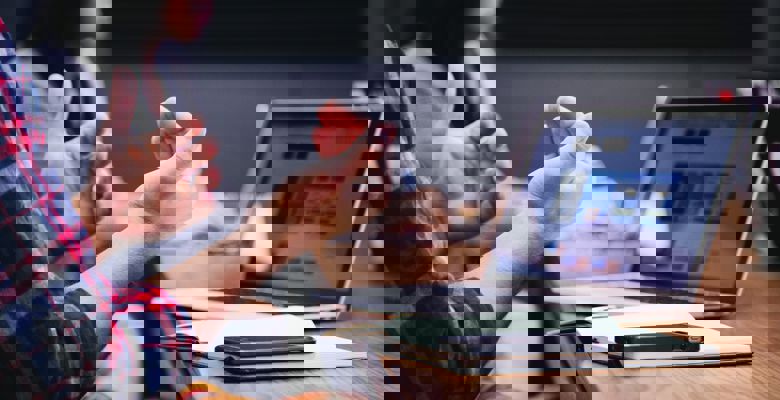 Person talking while making hand movements. Their laptop and notebook is open on the desk in front of them.