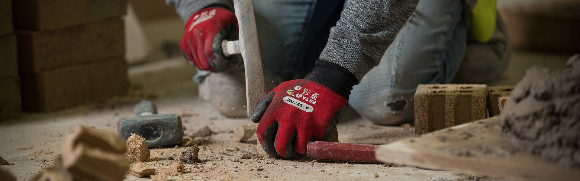 Construction student breaking up bricks in order to build a wall.