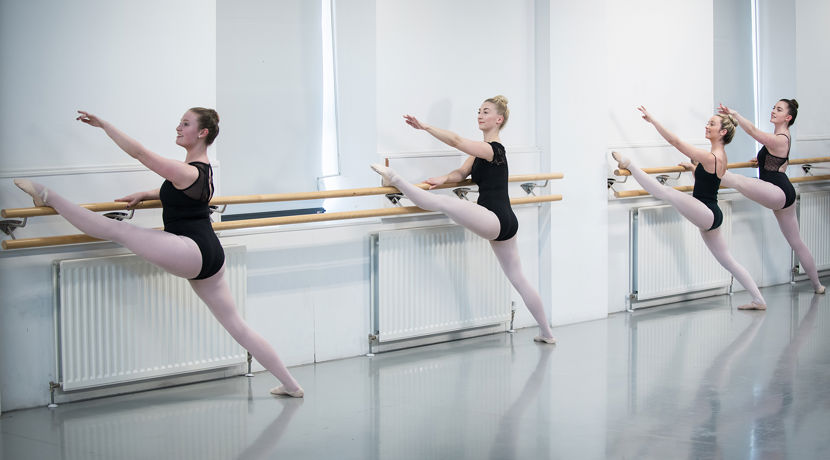 Dance students working on their ballet technique in a dance studio.