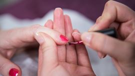 Close up of beauty student applying nail polish.